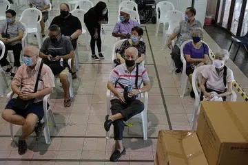 SAMBUTAN MENGGALAKKAN: Warga emas mula menerima suntikan penggalak bagi mengekang Covid-19 seiring individu lain. Gambar dirakam di ruang pemantauan sejurus selepas mereka disuntik di Kelab Masyarakat Tanjong Pagar kelmarin. - Foto BH oleh NG SOR LUAN