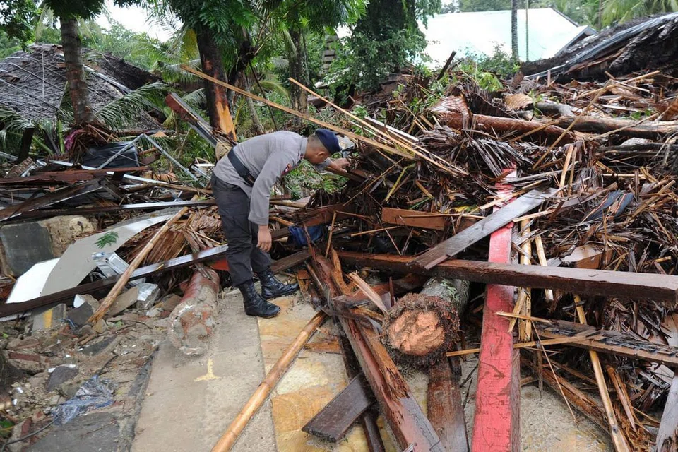 CARI MANGSA: Seorang anggota polis Indonesia mencari mangsa-mangsa di bawah runtuhan Mutiara Carita Cottages di Carita, Banten semalam. - Foto AFP