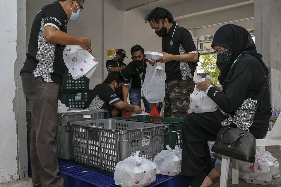 SEBAR KECERIAAN: Para relawan membungkus beriani ke dalam beg plastik yang diagihkan kepada keluarga-keluarga kelmarin. - Foto BH oleh YONG LI XUAN
