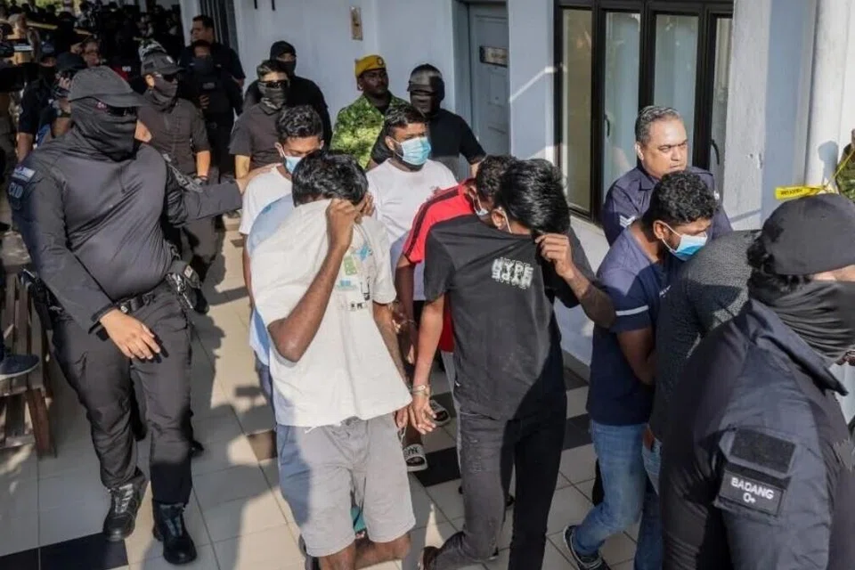 Anggota polis (berpenutup muka) mengawasi sebahagian 11 suspek kumpulan jenayah kekerasan ‘Geng Vinod’ untuk didakwa di Mahkamah Sepang, Selangor, pada 24 Julai.
