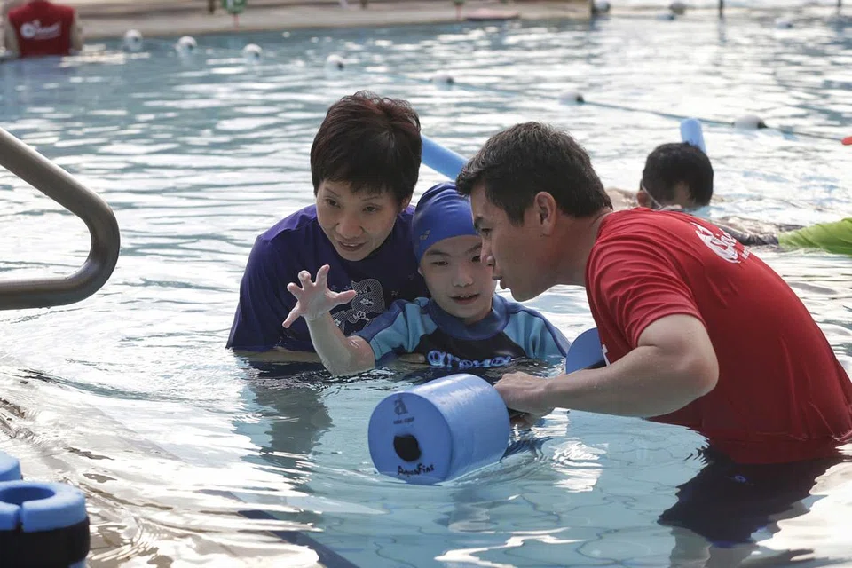 GALAK WARGA KURANG UPAYA BERSUKAN: Cik Fu (kiri) mencuba sendiri program renang bersama kanak kecil kurang upaya Teo Choon Khang (tengah) dan pelatih renang bagi orang kurang upaya, Encik Danny Ong - Foto THE STRAITS TIMES