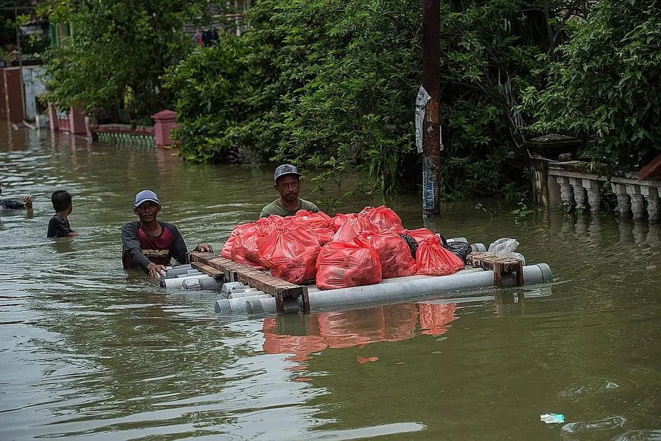 HARUNGI CABARAN: Penduduk meninggalkan kediaman yang dinaiki air di Gresik, Jawa Timur pada 15 Disember lalu, akibat musim hujan yang melanda banyak kawasan Jakarta dan Tanah Jawa di Indonesia. - Foto AFP 
