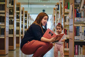 PUPUK MINAT MEMBACA: Cik Nadia Ahmad Samdin membaca buku dengan seorang kanak-kanak di perpustakaan Ang Mo Kio. - Foto FACEBOOK NADIA AHMAD SAMDIN