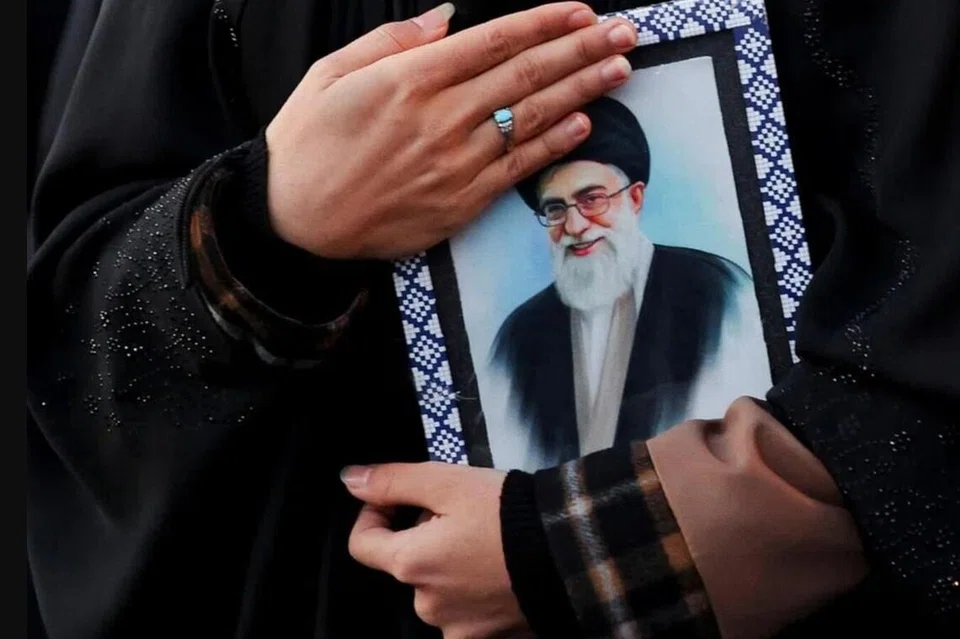 Seorang wanita memegang gambar pemimpin agama tertinggi  Iran Ayatollah Ali Khamenei di Dataran Enghelab, selepas beliau terbunuh dalam serangan Israel dan Amerika Syarikat pada hari Sabtu, di Tehran, Iran, 1 Mac 2026.