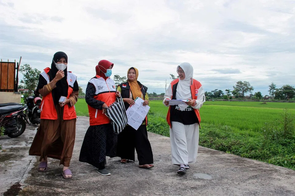 Cik Lingga Permesti (kanan), calon perundangan bagi Parti Keadilan Sejahtera Islam (PKS), berjalan bersama sukarelawan untuk melawat dari rumah ke rumah ketika beliau berkempen menjelang pilihan raya di Klaten, Jawa Tengah.