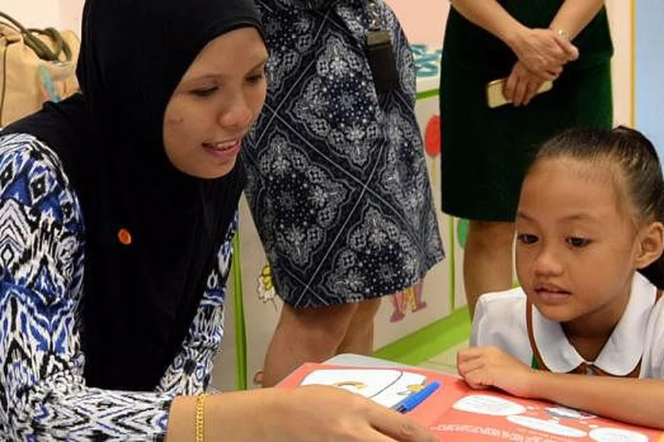 KEGIATAN BERSAMA: Cik Siti Rohmiati melakukan kegiatan yang terdapat dalam buku kegiatan hasil MOE bersama anaknya, Nur Khodiijah Hasri, bagi membantu si kecil mengharungi hari pertama di sekolah.