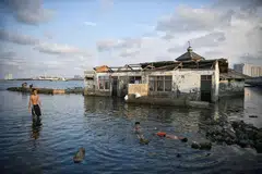 ANGKARA TANAH MENDAP: Kanak-kanak bermain dekat sebuah masjid yang ditinggalkan di Muara Baru, Jakarta Utara. Jakarta antara bandar paling cepat tenggelam di dunia. Tembok laut sepanjang lapan kilometer sedang dibina dari Pelabuhan Muara Baru ke Pelabuhan Sunda Kelapa bagi membantu menghalang air laut masuk. - Foto THE STRAITS TIMES