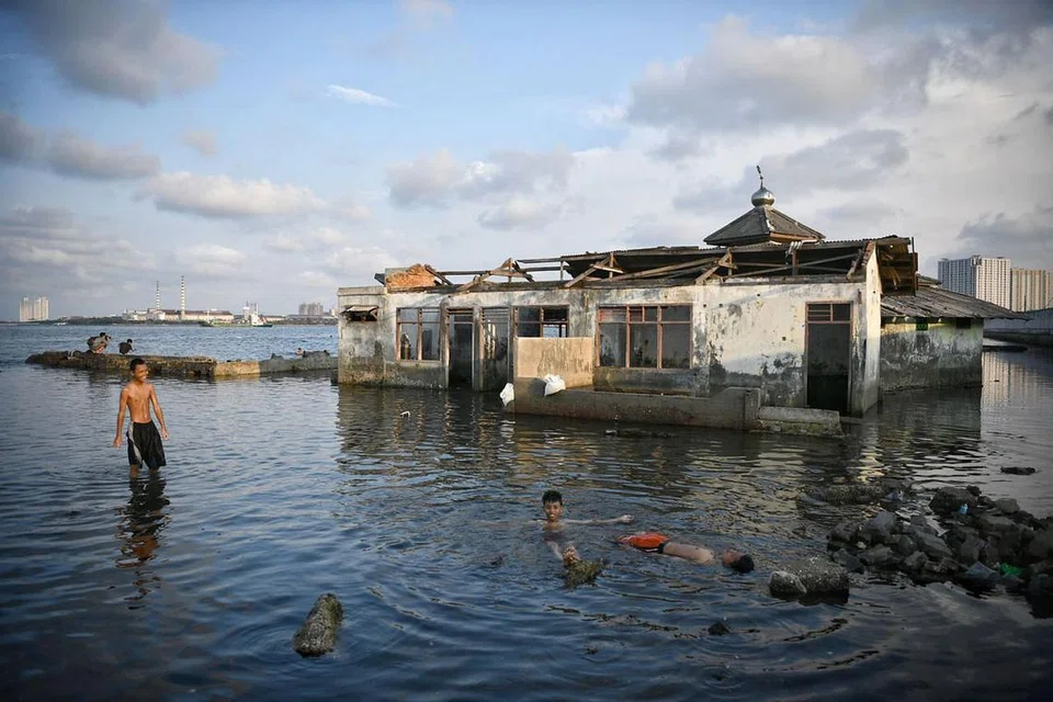 ANGKARA TANAH MENDAP: Kanak-kanak bermain dekat sebuah masjid yang ditinggalkan di Muara Baru, Jakarta Utara. Jakarta antara bandar paling cepat tenggelam di dunia. Tembok laut sepanjang lapan kilometer sedang dibina dari Pelabuhan Muara Baru ke Pelabuhan Sunda Kelapa bagi membantu menghalang air laut masuk. - Foto THE STRAITS TIMES
