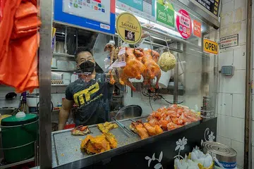 SUDAH SESUAIKAN DIRI: Encik Mohammad Noorham Nordin kelihatan menyediakan makanan di gerainya bernama TAKDeNAMA di pusat penjaja di tingkat dua, Pasar Geylang Serai.