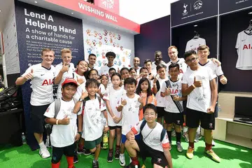 USAHA MURNI: Para pemain bola sepak Tottenham Hotspur (di barisan belakang) bergambar dengan kanak-kanak Children's Wishing Well, yang merupakan pertubuhan kebajikan yang mendapat sokongan AIA Singapore. Acara berlangsung pada Sabtu lalu di Hab Sukan Singapura. - Foto AIA SINGAPORE