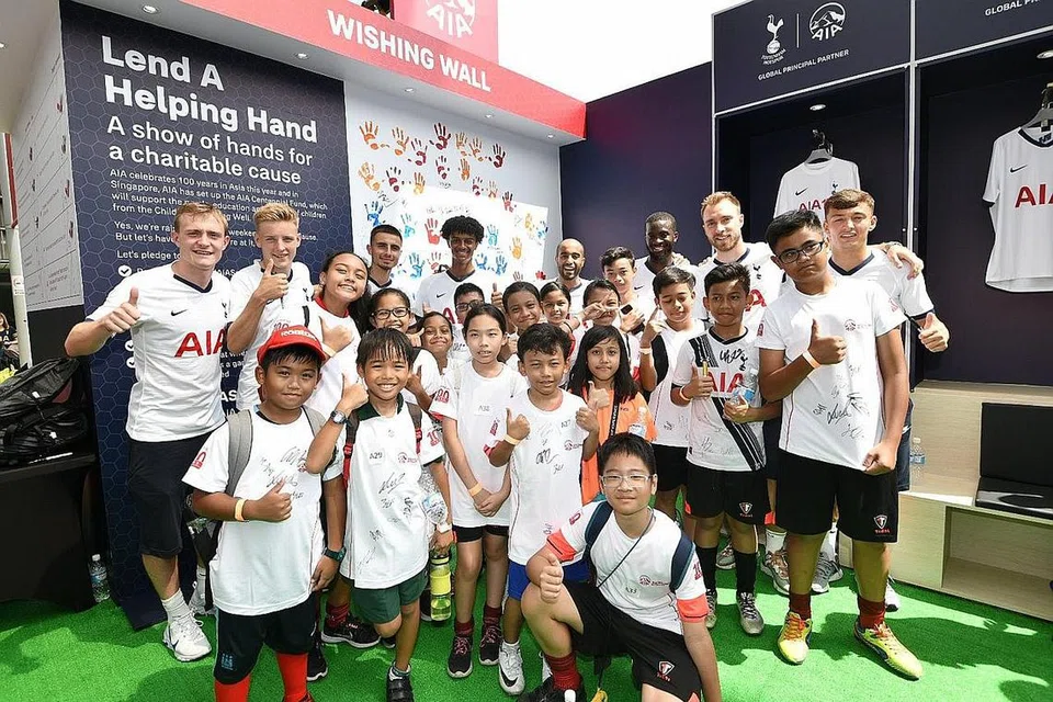 USAHA MURNI: Para pemain bola sepak Tottenham Hotspur (di barisan belakang) bergambar dengan kanak-kanak Children's Wishing Well, yang merupakan pertubuhan kebajikan yang mendapat sokongan AIA Singapore. Acara berlangsung pada Sabtu lalu di Hab Sukan Singapura. - Foto AIA SINGAPORE
