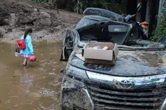 Seorang wanita meredah kawasan tanah berlumpur akibat hujan lebat di Kampung Semangat Gunung di Karo, wilayah Sumatera Utara, Indonesia, pada 25 November 2024.
