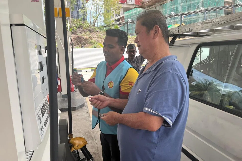 Warga emas, Encik Lee Tik Wah, 60 tahun (kanan), dibantu pembantu pam di sebuah stesen minyak di Kuala Lumpur, untuk mendapatkan manfaat petrol bersubsidi bermula 30 September.
