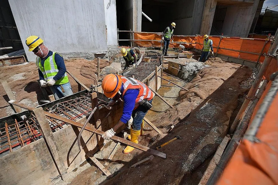 RANCAK SEMULA: Pekerja pembinaan memakai helmet dan jalur pergelangan tangan yang berwarna bagi mengenal pasti zon mana tempat tugasan mereka di tapak binaan BTO Senja Valley. - Foto BH oleh NG SOR LUAN