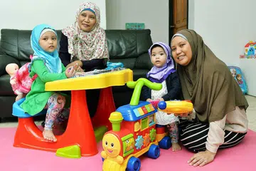 BERHENTI KERJA JAGA CUCU: Cik Zaliha Ahmad (kiri), 53 tahun, gembira diberi peluang oleh anaknya, Cik Siti Munirah (kanan), 32 tahun, menjaga cucunya - Nor Ayla Nor Andi (kiri), empat tahun; dan Nor Arfa, satu tahun - selagi dirinya masih kuat. - Foto KHALID BABA