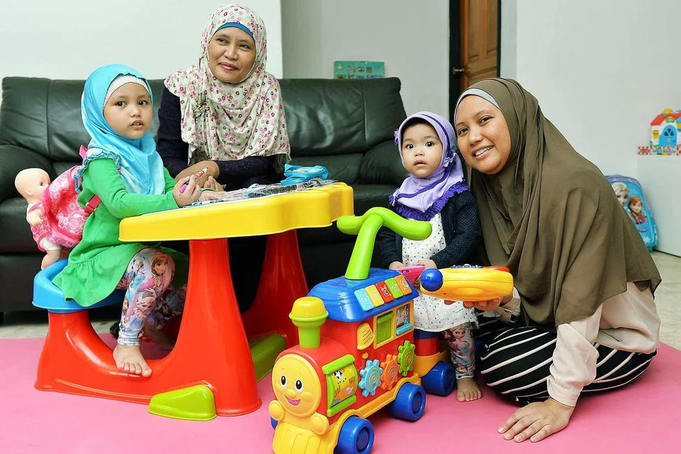 BERHENTI KERJA JAGA CUCU: Cik Zaliha Ahmad (kiri), 53 tahun, gembira diberi peluang oleh anaknya, Cik Siti Munirah (kanan), 32 tahun, menjaga cucunya - Nor Ayla Nor Andi (kiri), empat tahun; dan Nor Arfa, satu tahun - selagi dirinya masih kuat. - Foto KHALID BABA