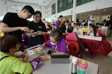 Penduduk mendapat bantuan bagi alat-alat digital mereka di pembukaan rasmi Kelab Masyarakat Kaki Bukit dipertingkat pada 8 Jun.