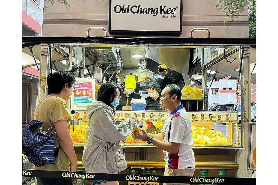 AGIH SARAPAN PERCUMA: Anggota Parlimen bagi GRC Choa Chu Kang, Encik Zhulkarnain Abdul Rahim (kanan), mengagihkan set sarapan percuma dari trak makanan Old Chang Kee kepada penduduk di kawasan itu pada Ahad lalu. - FOTO FACEBOOK ZHULKARNAIN ABDUL RAHIM