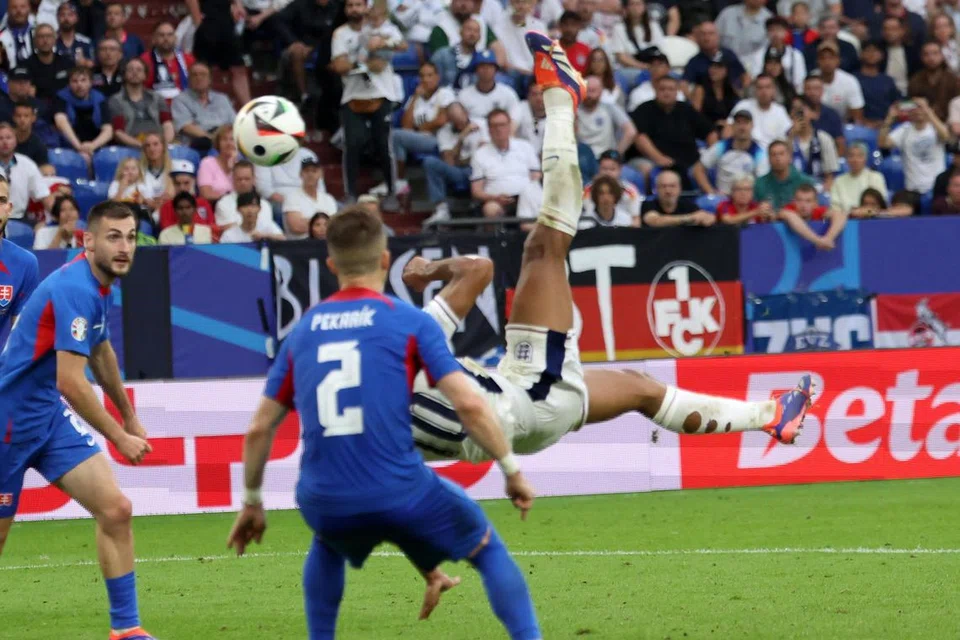 Pemain England, Jude Bellingham (atas, kanan), menjaringkan gol penyamaan akrobatik saat akhir, yang berjaya mengheret perlawanan ke masa tambahan, dan menyaksikan England menang 2-1 ke atas Slovakia dalam perlawanan peringkat 16 pasukan terakhir Euro 2024 di Arena Aufschalke pada 30 Jun. 