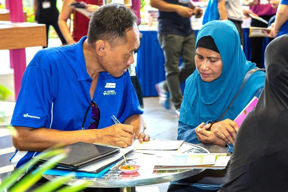 KHIDMAT PEMADANAN KERJAYA: Kakitangan Tenaga Kerja Singapura (WSG) menerangkan kepada seorang peserta tentang Khidmat Careers Connect On-the-Go (CCOTG) yang disediakan WSG di pameran 'Raikan Ilmu@South East'. - Foto BH oleh ZALEHA ABDUL KADER