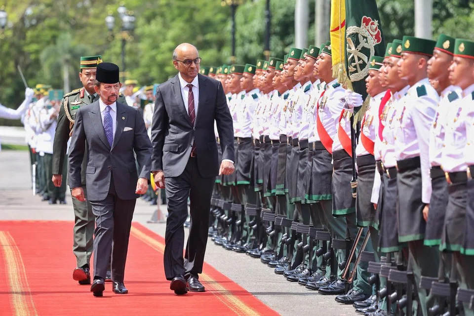 SAMBUTAN PENUH ISTIADAT: Presiden Tharman Shanmugaratnam (kanan), ditemani Sultan Brunei, Sultan Hassanal Bolkiah (kiri), memeriksa anggota Angkatan Bersenjata Diraja Brunei setelah beliau tiba di Istana Nurul Iman pada 25 Januari.