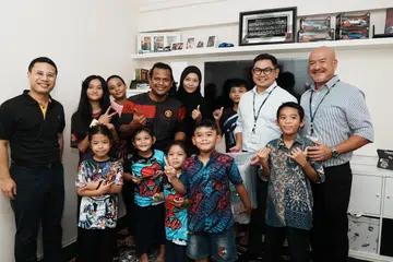 Encik Muhammad Rahmat (empat dari kiri, barisan belakang), bersama keluarganya, antara 1,700 keluarga yang akan meraih manfaat hasil kerjasama Kementerian Pembangunan Sosial dan Keluarga (MSF) dengan Ikea, yang bertujuan mempertingkat sokongan bagi keluarga berpendapatan lebih rendah. Bersama mereka ialah Menteri Pembangunan Negara, Encik Desmond Lee (kiri, barisan belakang).