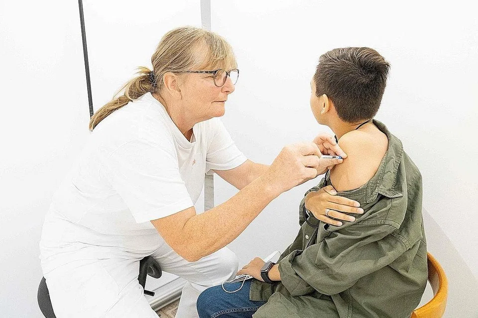 BIMBANG ADA KESAN SAMPINGAN: Seorang kakitangan perubatan memberi suntikan vaksin di sebuah pusat vaksinasi sementara di pasar raya Bilka di Ishoej, Denmark, bagi menarik golongan muda. Kelmarin, pihak berkuasa mengumumkan individu di bawah usia 18 tahun tidak akan diberi vaksin Moderna sebagai langkah berjaga-jaga. - Foto AFP