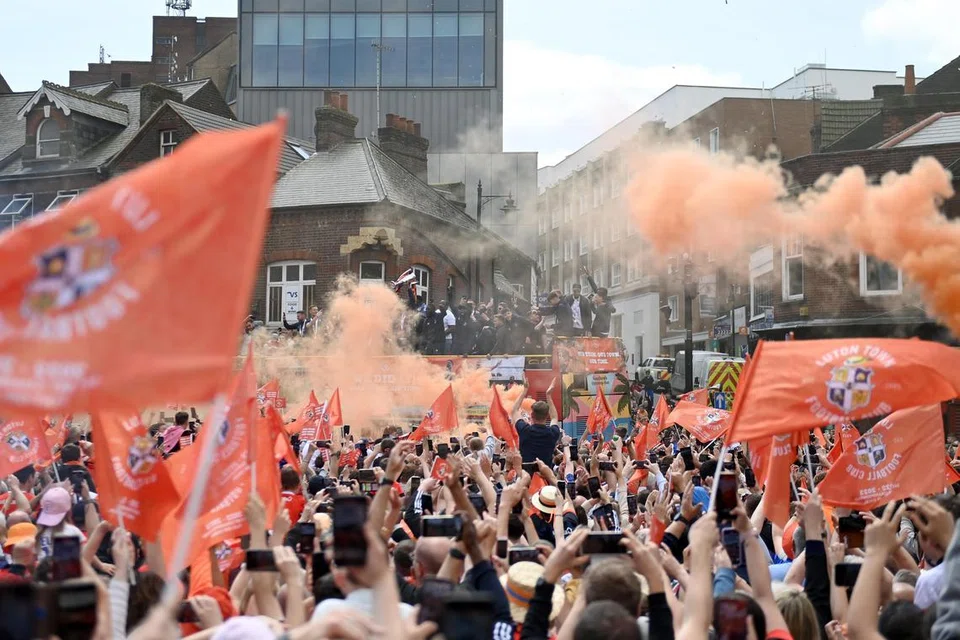 SAMBUTAN RAKSASA: Penyokong Luton membanjiri jalan raya yang dilalui bas membawa pasukan bola sepak Luton Town semasa ia berarak untuk meraikan promosi pasukan itu ke Liga Perdana England (EPL). 