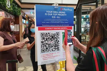 IMBAS KOD QR: Seorang pelanggan sedang mengimbas kod QR sebelum memasuki sebuah cawangan NTUC FairPrice.