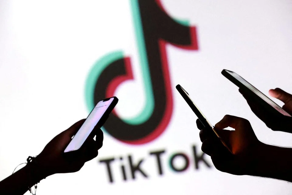 Remaja bergambar sambil memegang telefon pintar di hadapan logo TikTok dalam ilustrasi yang diambil pada 11 September 2025.