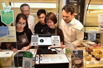BERI PELUANG SAMA RATA: Menteri Negara (Sosial dan Pembangunan Keluarga merangkap Ehwal Luar), Encik Sam Tan (kiri) dan Encik Zaqy menyaksikan bagaimana Foreword Coffee berjaya melaksana proses mereka semula tugas khusus bagi menampung golongan berkeperluan khas. - Foto BH oleh DESMOND WEE
