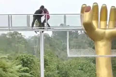 CUBA SELAMATKAN: Pengunjung yang melewati jambatan kaca The Geong membantu salah seorang mangsa yang berpaut pada rangka jambatan setelah salah satu lantai panel kaca jambatan itu pecah pada Rabu.