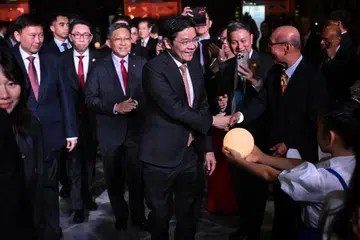Perdana Menteri Encik Lawrence Wong (tengah), Presiden Dewan Perniagaan dan Perusahaan Cina Singapura (SCCCI) Encik Kho Choon Keng (ketiga dari kiri) dan Menteri Pembangunan Negara, Encik Chee Hong Tat (kiri) tiba untuk majlis makan malam gala ulang tahun ke-120 SCCCI pada 30 Oktober.