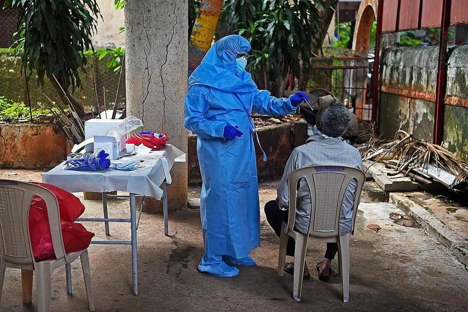 JALANI UJIAN: Seorang pekerja kesihatan sedang melakukan ujian Covid-19 ke atas seorang penduduk di satu tempat kediaman di Mumbai semalam. - Foto AFP