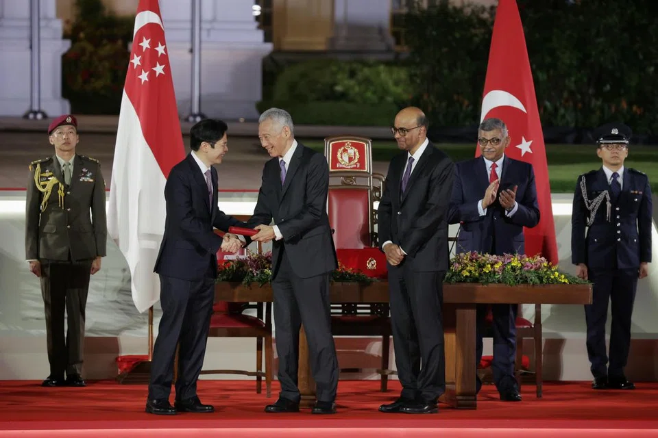 Perdana Menteri, Encik Lawrence Wong (kiri), bersalaman dengan Menteri Kanan, Encik Lee Hsien Loong, di Istana pada 15 Mei, disaksikan Presiden Tharman Shanmugaratnam (tengah) dan Ketua Hakim Sundaresh Menon (kanan).