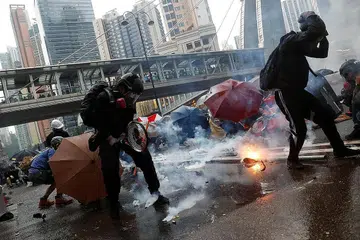 LINDUNGI DIRI: Para penunjuk perasaan berlindung daripada gas pemedih mata yang dilontar pegawai polis semasa demontrasi di Tsuen Wan, Hongkong, semalam. - Foto REUTERS