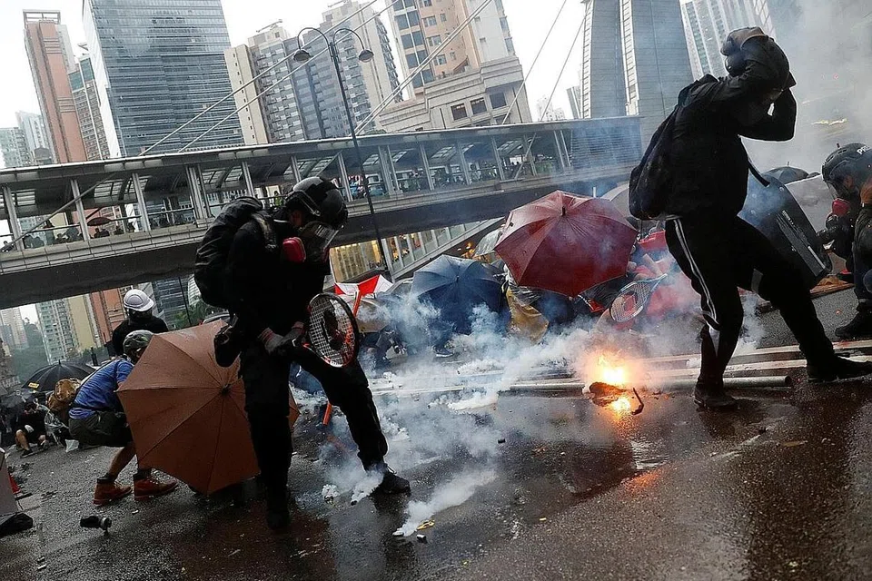 LINDUNGI DIRI: Para penunjuk perasaan berlindung daripada gas pemedih mata yang dilontar pegawai polis semasa demontrasi di Tsuen Wan, Hongkong, semalam. - Foto REUTERS