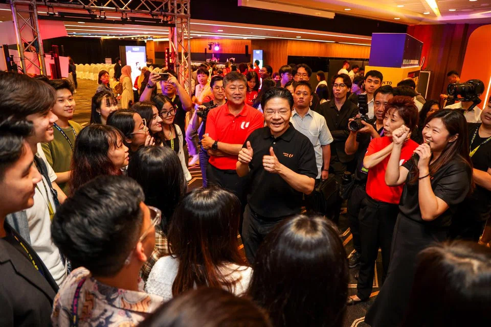 INTERAKSI DENGAN BELIA: Encik Lawrence Wong (tengah, berbaju hitam) dan Encik Ng Chee Meng (tengah, berbaju merah) meninjau pameran Hab Belia semasa simposium tahunan NTUC Muda, LIT DISCOvery 2023, di Pusat Konvensyen dan Pameran Suntec Singapura pada Jumaat.
