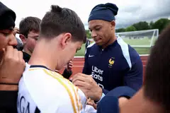 Penyerang Perancis, Kylian Mbappe (jersi biru), memberi autograf kepada peminat dengan jersi Real Madrid sebelum latihan pasukan kebangsaan Perancis menjelang saingan Euro 2024. 