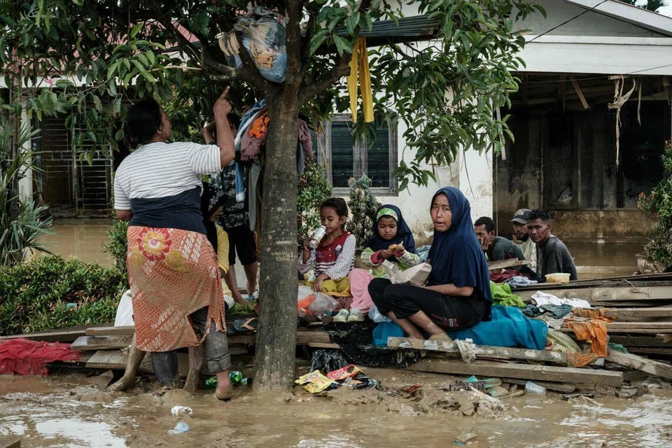 Orang ramai berkumpul di bawah sepohon pokok untuk berlindung daripada hujan susulan kejadian banjir kilat kira-kira tiga minggu lalu di Aceh Tamiang, Sumatera Utara, pada 16 Disember 2025. 