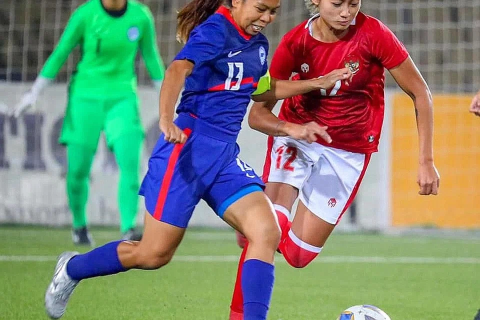 TETAP BERJUANG: Kapten pasukan nasional Ernie Sontaril (jersi biru) cuba menggelecek bola daripada seorang pemain Indonesia dalam perlawanan kelayakan Piala Asia di Tajikistan kelmarin. Singapura tewas 0-1 dan gagal melayakkan diri ke pertandingan utama di India tahun depan. - Foto FAS