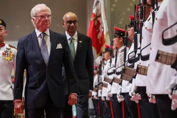 Raja Sweden Carl XVI Gustaf (kiri) memeriksa kawalan kehormatan bersama Presiden Tharman Shanmugaratnam di Parliament House di Singapura pada 19 November.