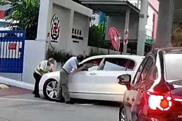 TUKAR NOMBOR PLAT: Rakaman video Neo Hong Chye memandu untuk memasuki Sekolah Red Swastika walau dihalang seorang pegawai keselamatan. Anak Neo, Glynn Neo, menukar nombor plat kereta itu untuk sesi foto bagi menjualnya. - Foto SGRV/FACEBOOK