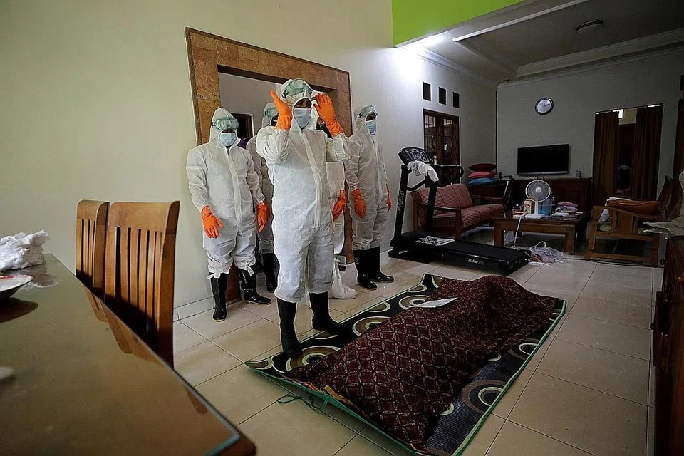 MENYEMPURNAKAN JENAZAH: Anggota polis lengkap berpakaian pelindung diri melakukan sembahyang jenazah mangsa yang meninggal dunia pada usia 86 tahun akibat komplikasi yang ada kaitan dengan Covid-19 di Bogor, Indonesia. - Foto REUTERS