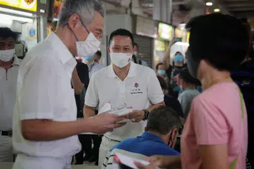 DEKATI PENDUDUK: Perdana Menteri Lee Hsien Loong (kiri) bersama calon PAP bagi SMC Yio Chu Kang, Encik Yip Hon Weng, bertemu penduduk di pusat penjaja di Blok 628 Ang Mo Kio Avenue 4 semalam. - Foto BH oleh JASON QUAH