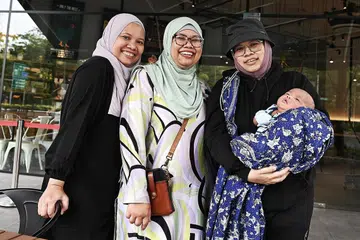 JANA KANDUNGAN 'MAKCIK STYLE': (Dari kiri) Tiga beradik Cik Sophiela Mustapha, Cik Aldila Mustapha, dan Cik Noorhayati Mustapha (yang mendukung cucu Cik Aldila) merupakan pengasas laman makcikalertsg di media sosial yang memaparkan pelbagai aspek gaya hidup golongan 'makcik' seperti mereka. - Foto BM oleh KHALID BABA 