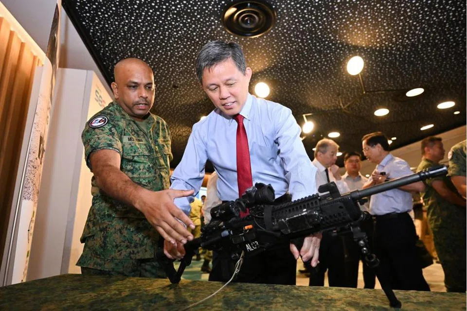 Pakar Tentera 3, Encik Muthukumaran Rangaswamy, jurutera pembangunan keupayaan dari Markas Divisyen 9/Infantri, menunjukkan senjata mesin ringan kepada Menteri Pertahanan, Encik Chan Chun Sing, pada upacara Hari SAF pada 1 Julai.