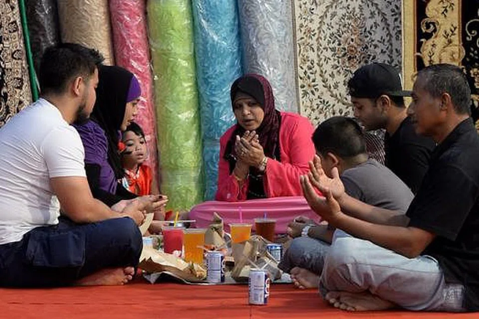 PANJATKAN KESYUKURAN: Keluarga ini membaca doa bersama-sama sebelum mencicipi juadah berbuka puasa yang terhidang di depan mereka. 
