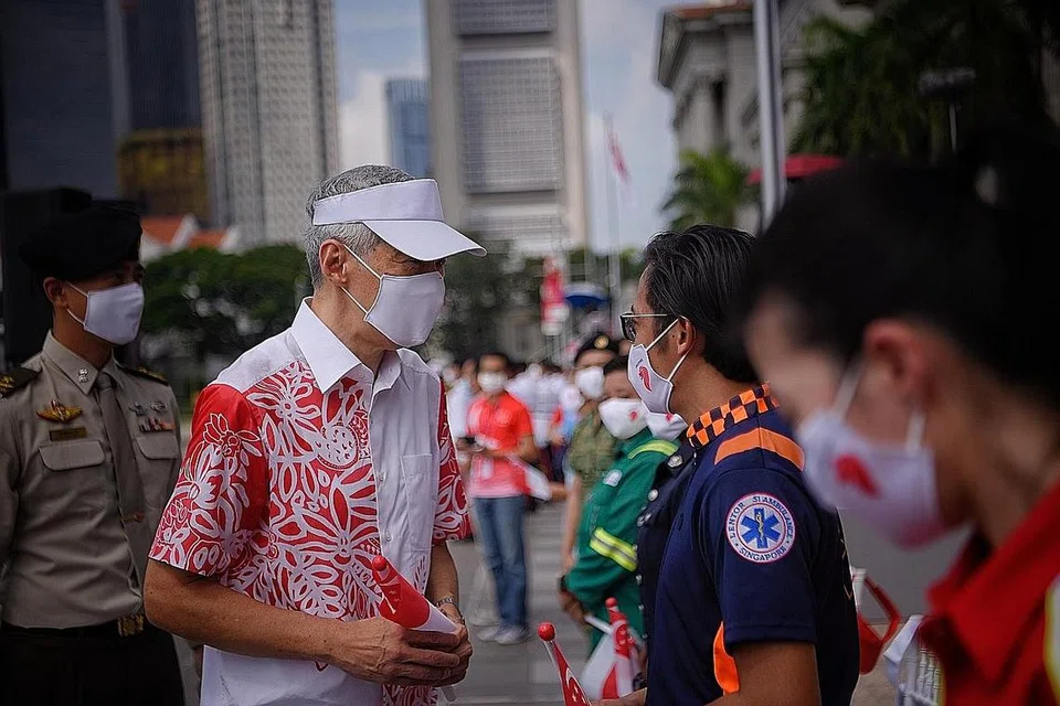 PENGHARGAAN: Perdana Menteri Lee Hsien Loong berinteraksi dengan Encik Muhammad Ferdauz Abdul Kadir, pemandu bas perubatan yang bertanggungjawab membawa pesakit Covid-19 dari hospital ke kemudahan penjagaan masyarakat. Beliau hadir bersama kakitangan barisan hadapan di Perbarisan Hari Kebangsaan di Padang pagi semalam. - Foto BH oleh MARK CHEONG