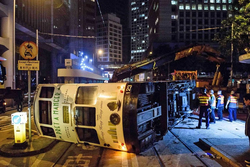 KEMALANGAN JARANG BERLAKU: Pegawai keselamatan meninjau trem dua tingkat yang terbalik di kawasan pusat bandar Hongkong kelmarin. - Foto AFP